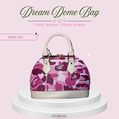 A structured dome-shaped handbag with a pink and purple camouflage pattern, displayed on a white tiered pedestal against a light pink background with promotional text.