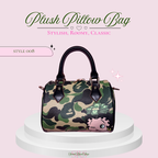 A plush pillow-style handbag with a green and black camouflage pattern, a pink cartoon pig graphic, and dark brown handles, displayed on a white pedestal against a light pink background with decorative text.